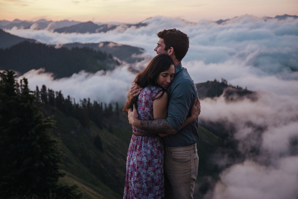 An adventurous couple embracing on the top  of Evergreen Mountain lookout, surrounded by clouds