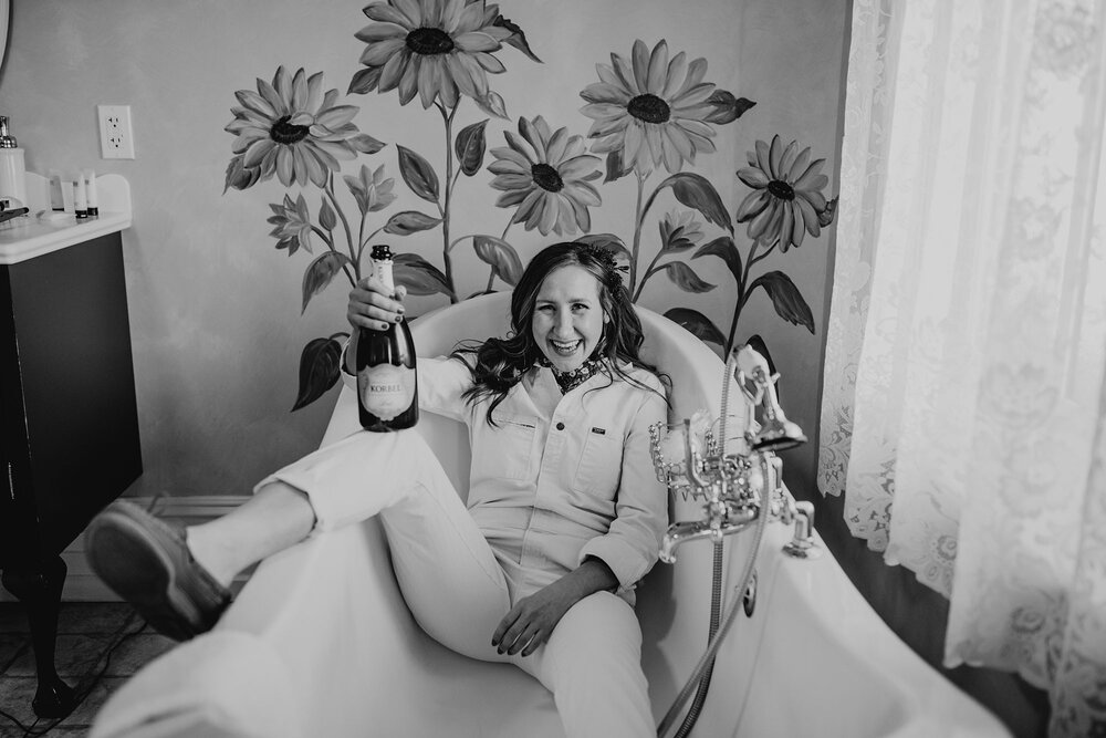 bride sitting in a bathtub with a bottle of champagne