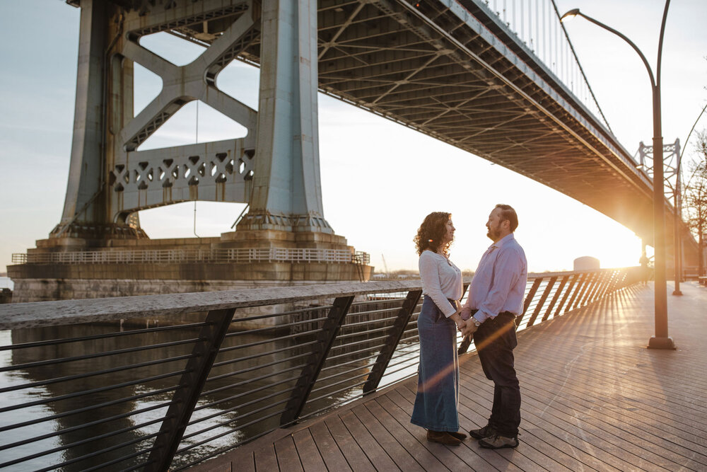 An engaged couple in from the of the Ben Franklin Bridge