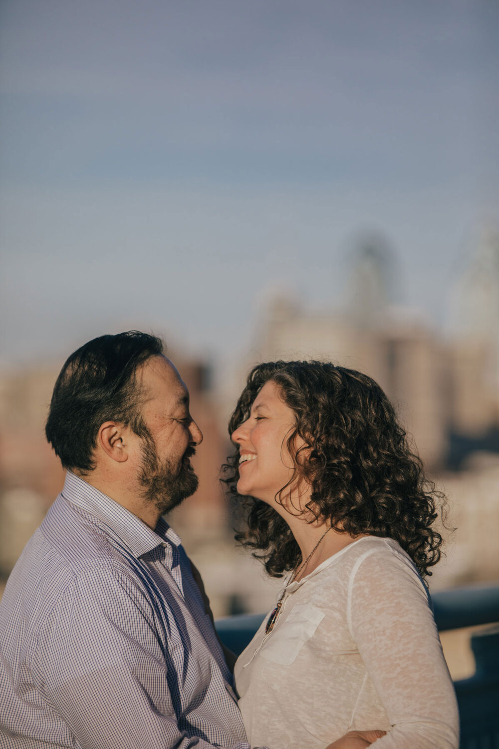 An engaged couple posing on the Ben Franklin Bridge