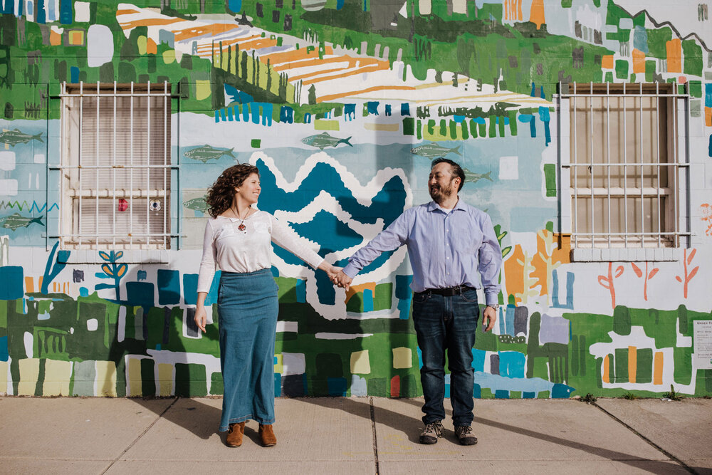 A couple standing in front of a mural in Philadelphia