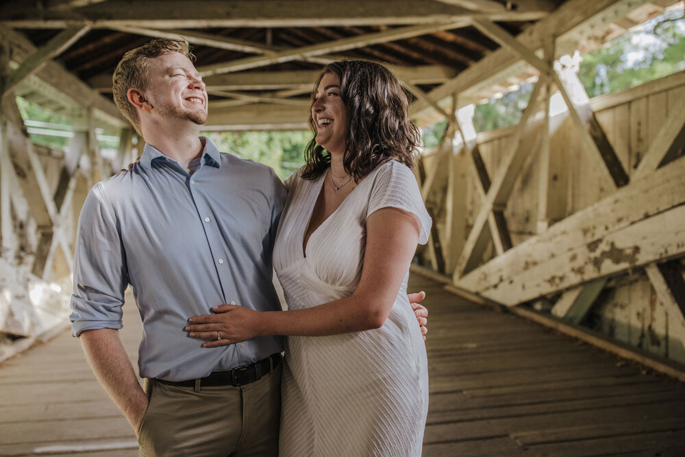 a couple posing inside of a covered bridge