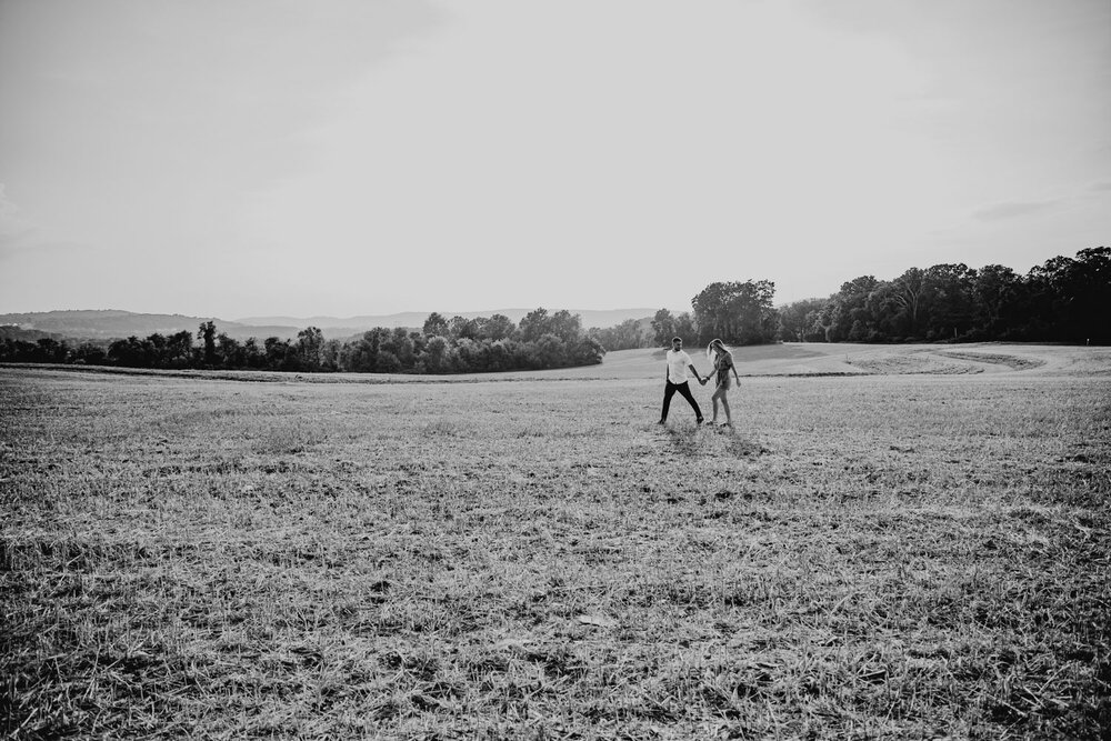 An engaged couple walking in a filed in the Lehigh Valley