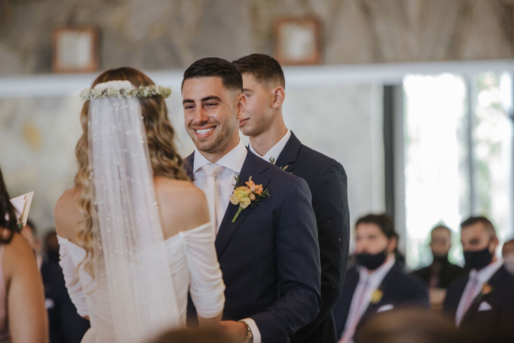 a groom smiles while he says his vows