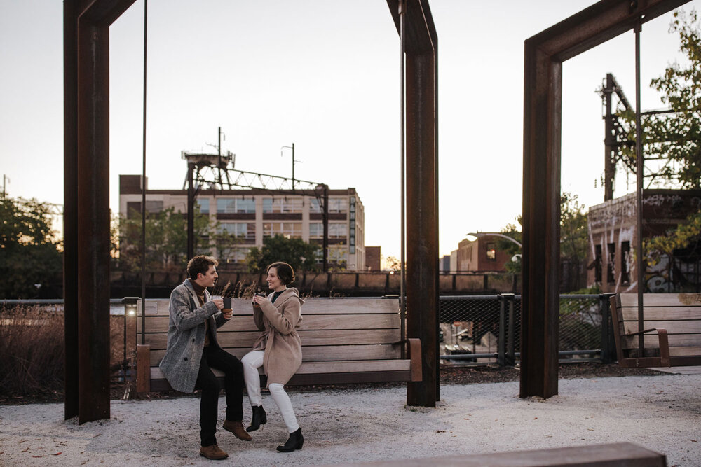 A couple sitting on a swing drinking coffee at Rail Park in Philadelphia