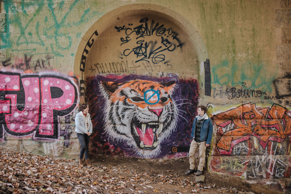 A couple posing with some graffiti in a photoshoot in Wissahickon Park