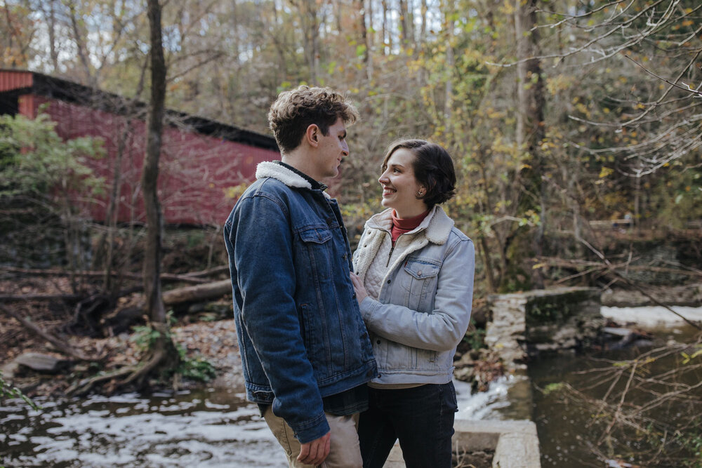 A couple photographed in front of a covered bridge in the Wissahickon Park