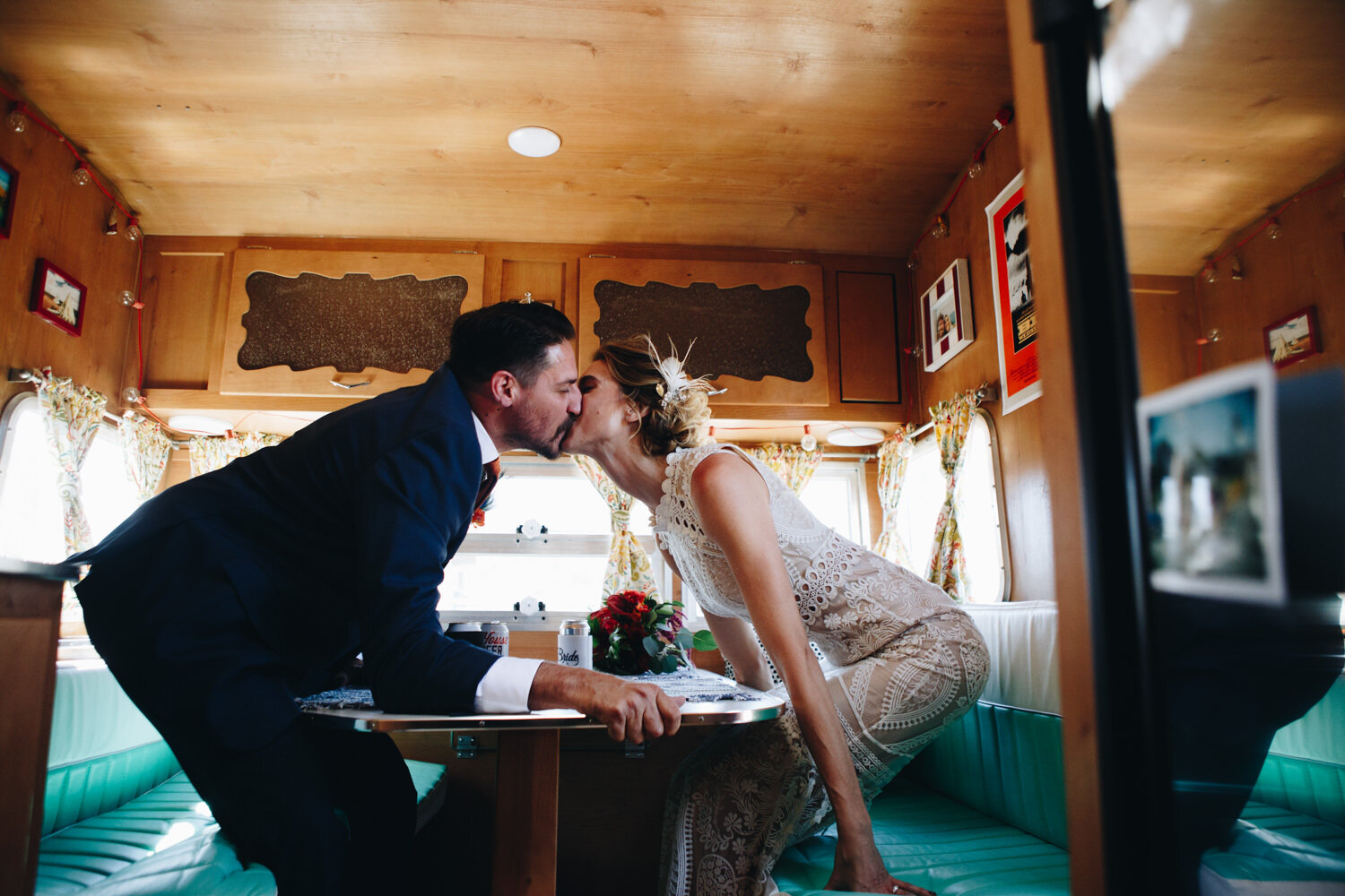 bride and groom leaning over a table to kiss 