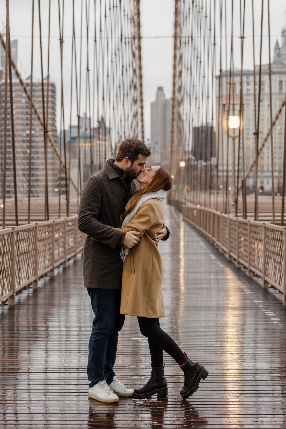 An engaged couple kissing in the middle of the Brooklyn Bridge