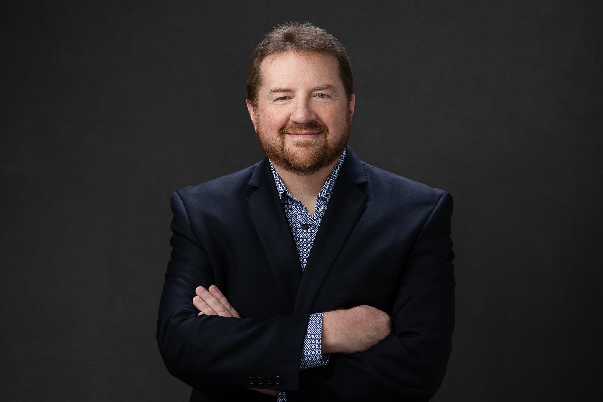 Business portrait of a man in a navy blazer with arms crossed