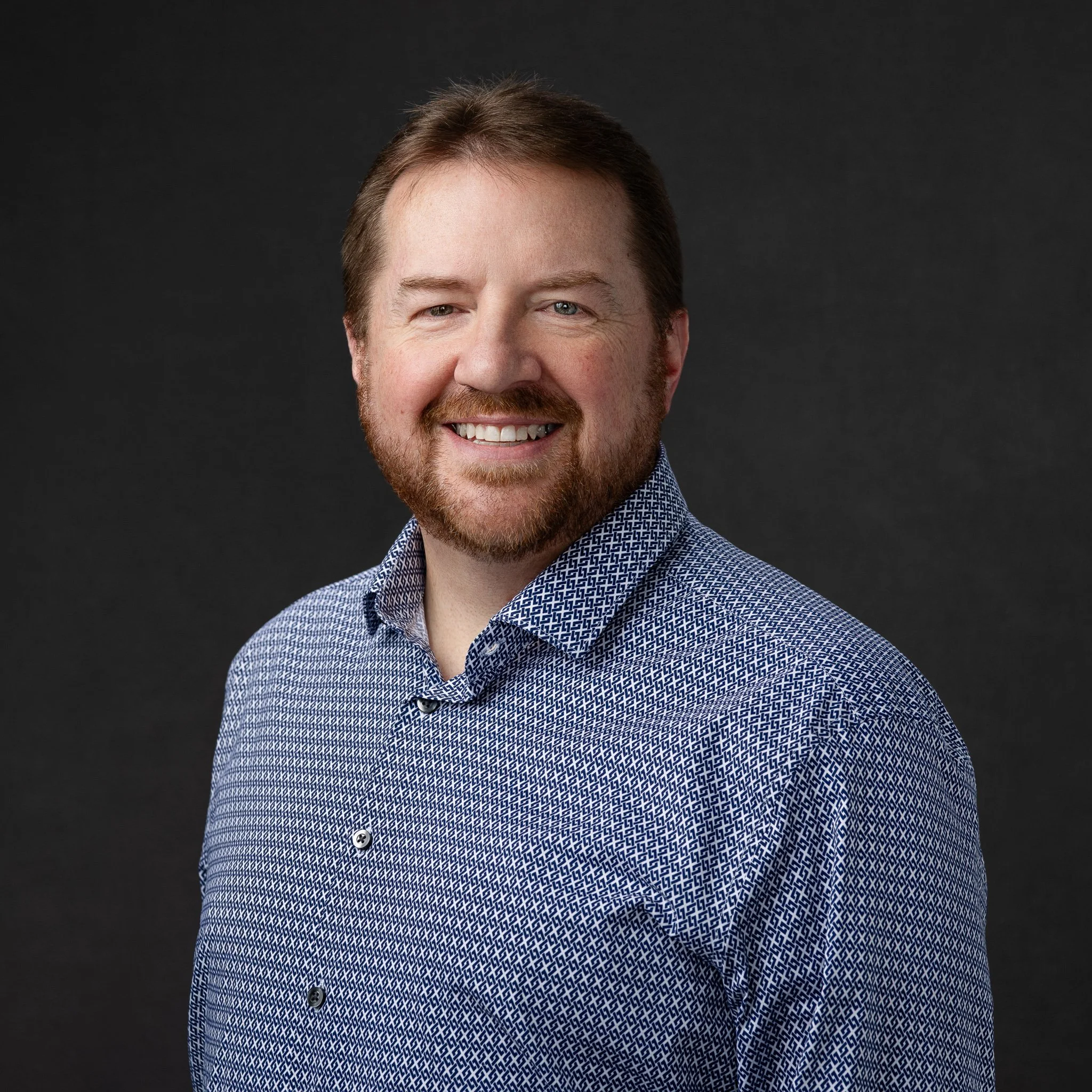 Casual professional headshot on a dark gray studio background