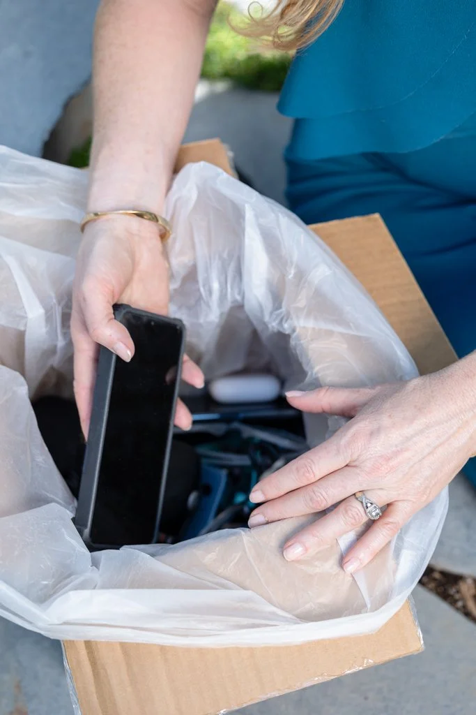Business owner placing used electronics into a recycling box during a custom branding photography session.
