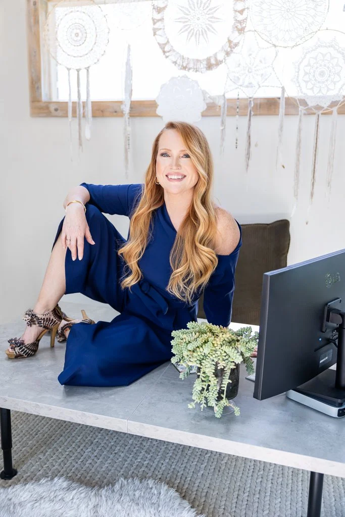 business owner sitting on desk next to computer smiling