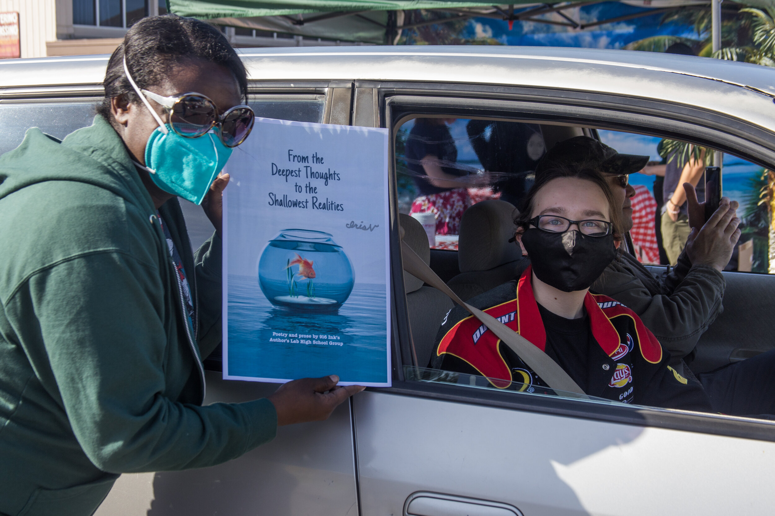 Board Member Dr. Beatrice Tetteh hands this student their poster to sign.