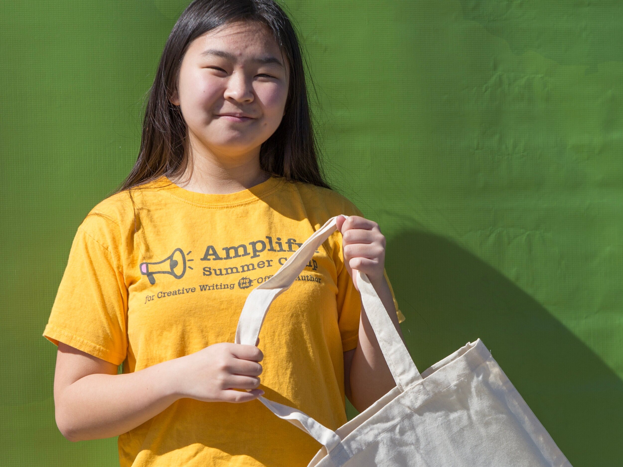 A student from Amplify! Summer Camps is excited to get her tote bag of goodies.
