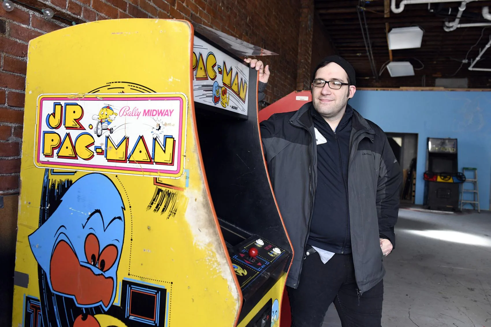 “Nick Grandchamp poses next to his Jr. Pac-Man machine Tuesday morning at a pop-up arcade gallery set to open this weekend.” Photo courtesy of Robert Layman / Rutland Herald Staff Photographer