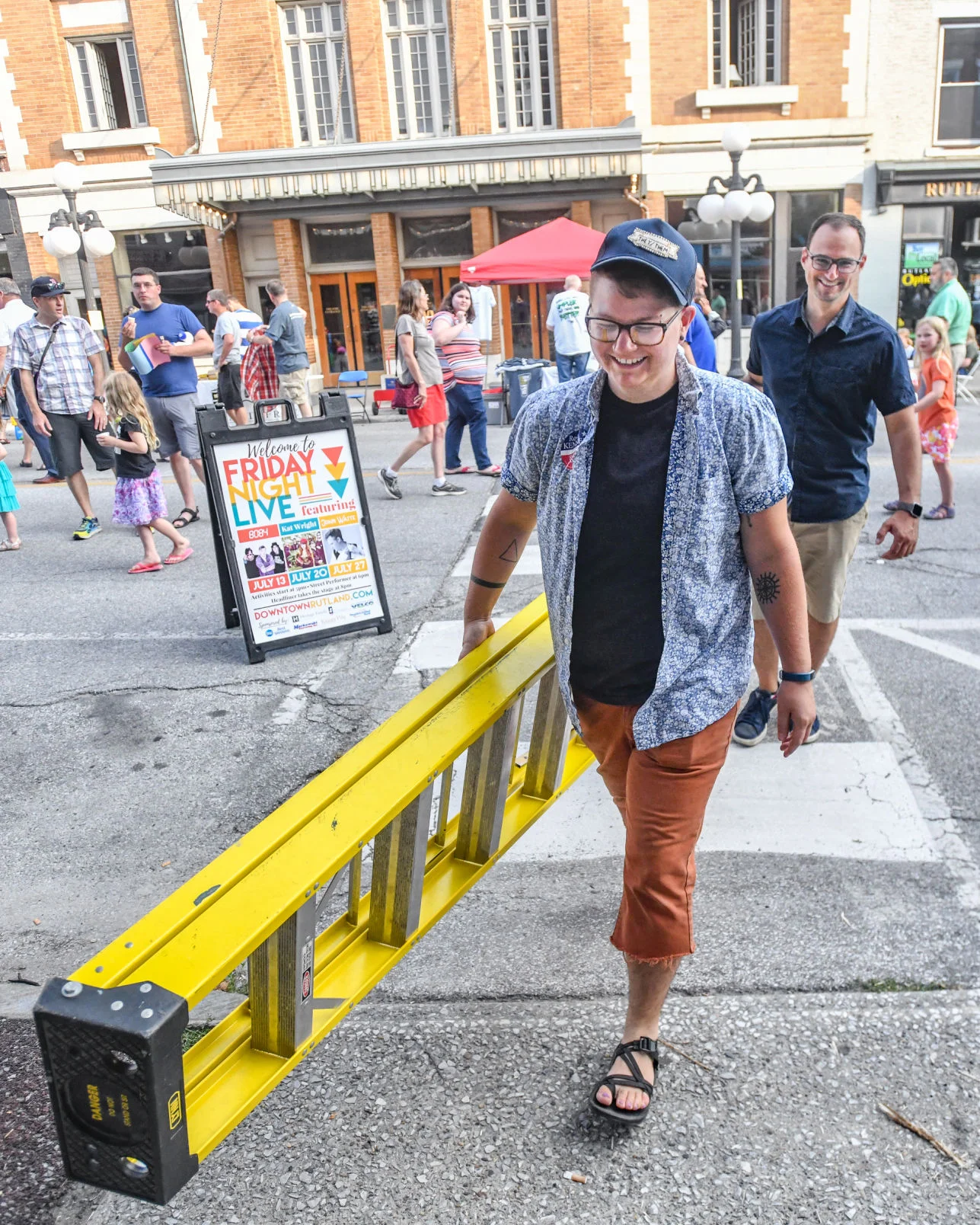 The Downtown Rutland Partnership’s Streetscape Coordinator, Jess Novak, and Steve Peters, Executive Director, move a ladder to hang extension cords at Friday Night Live 2018. Photo credit: Robert Layman / Rutland Herald