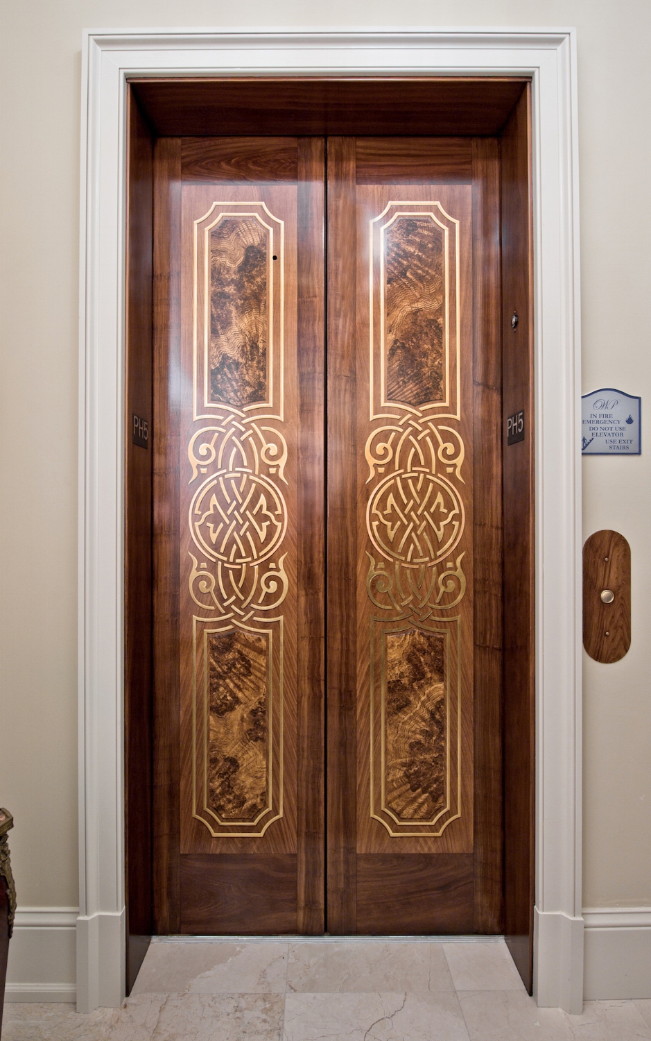  These stainless steel elevator doors were painted using a woodgraining technique. The custom design on the doors were gilded using Japanese Colored Silver Leaf. 