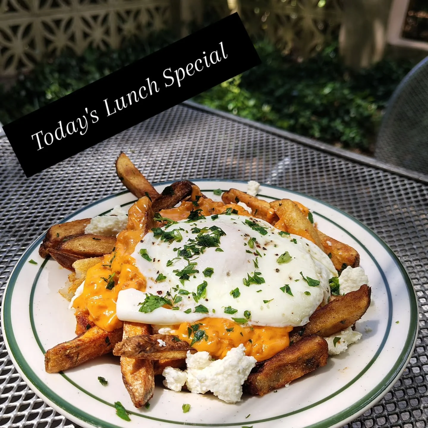 Chorizo Poutine, our signature french fries topped with chorizo gravy, queso fresco and a poached egg with herbs