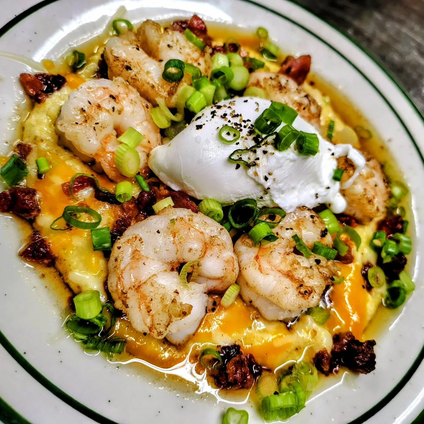 Shrimp and grits! 
Six butter seared shrimp, crispy bacon, our signature blend of gruyere, parmesan, cheddar, poached egg topped with scallions served over creamy Red Mule grits.