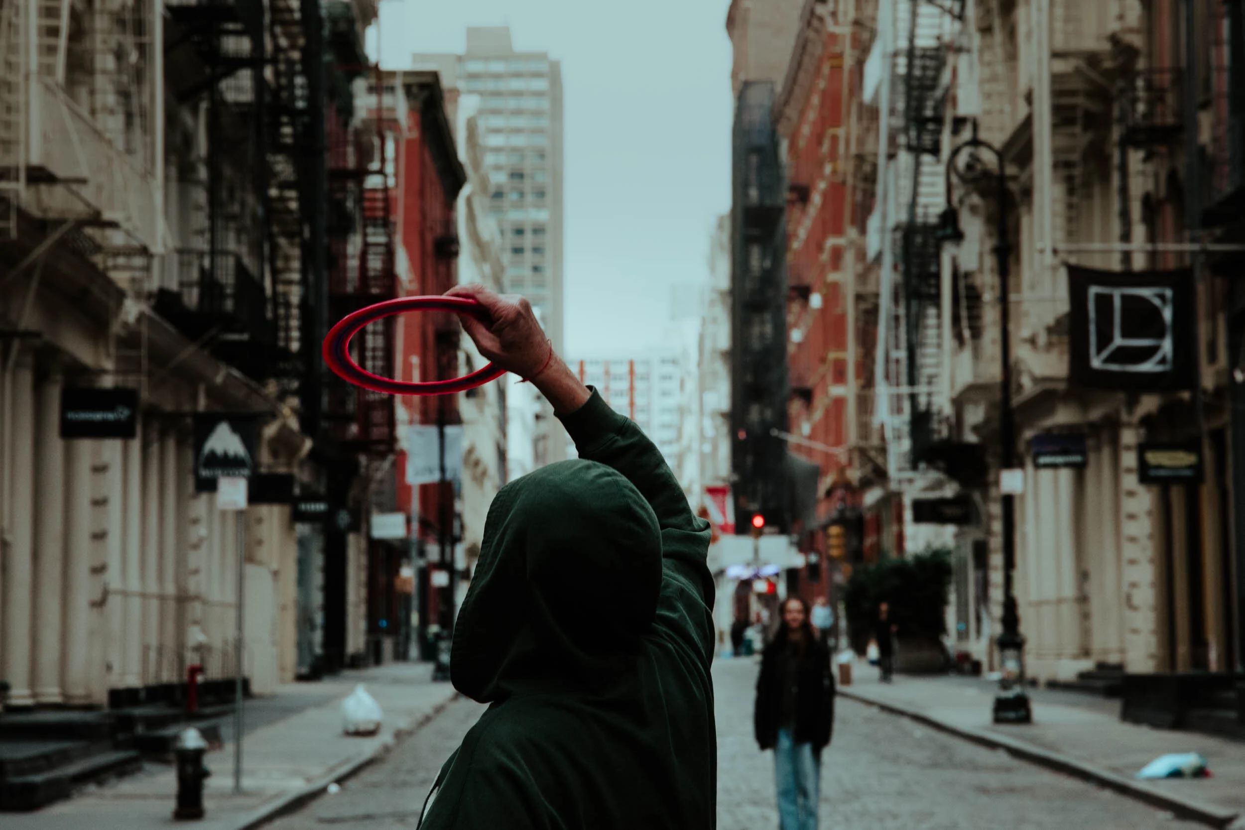  With no cars on the streets of SoHo, a father plays frisbee with his daughters in the middle of the cobblestone road. 