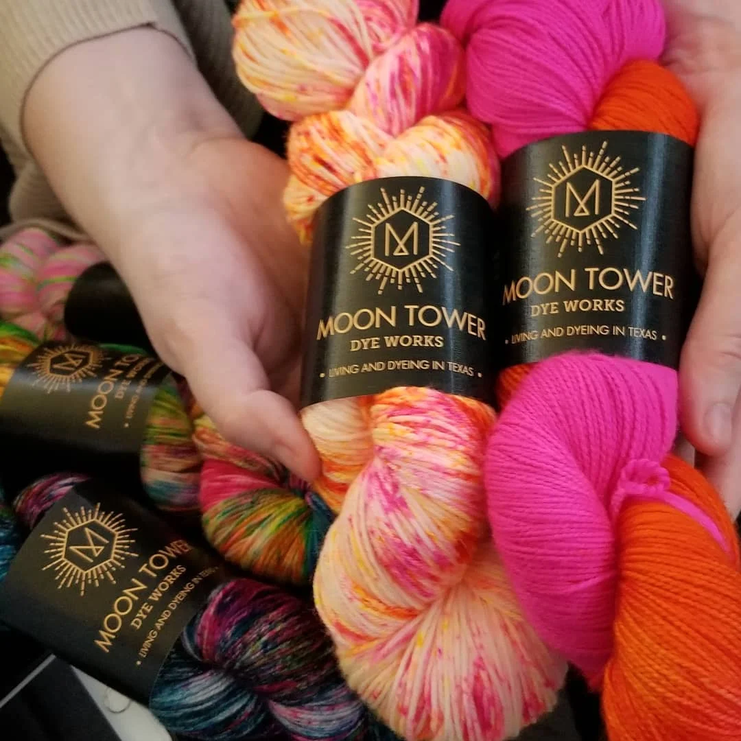 Hands holding pink yarn skeins from Moon Tower Dye Works.