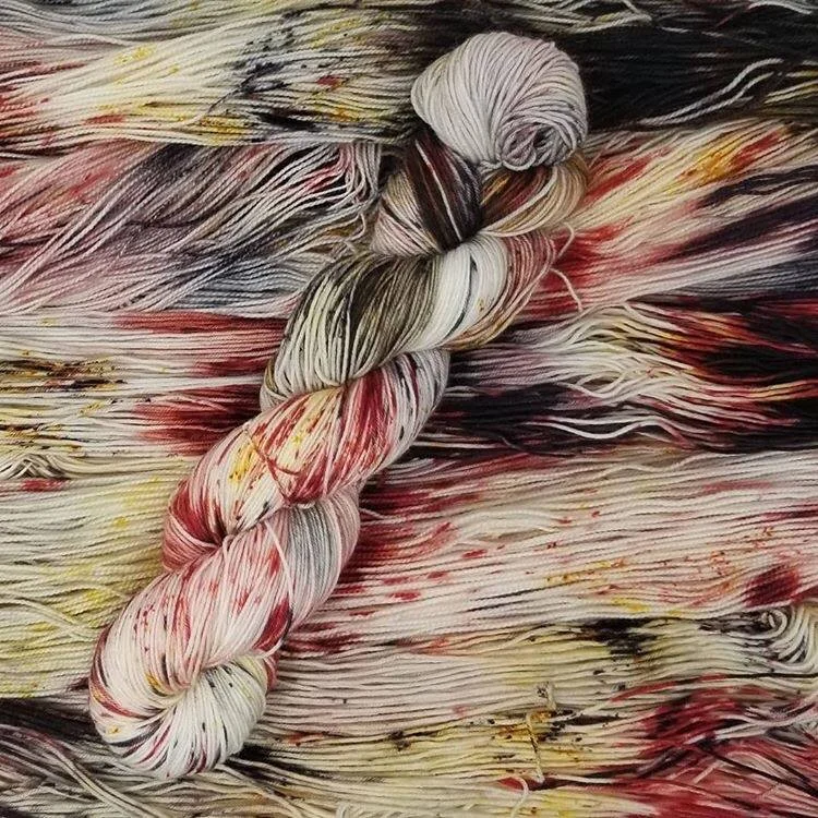 A skein of red and white variegated yarn sitting on more yarn of the same color.