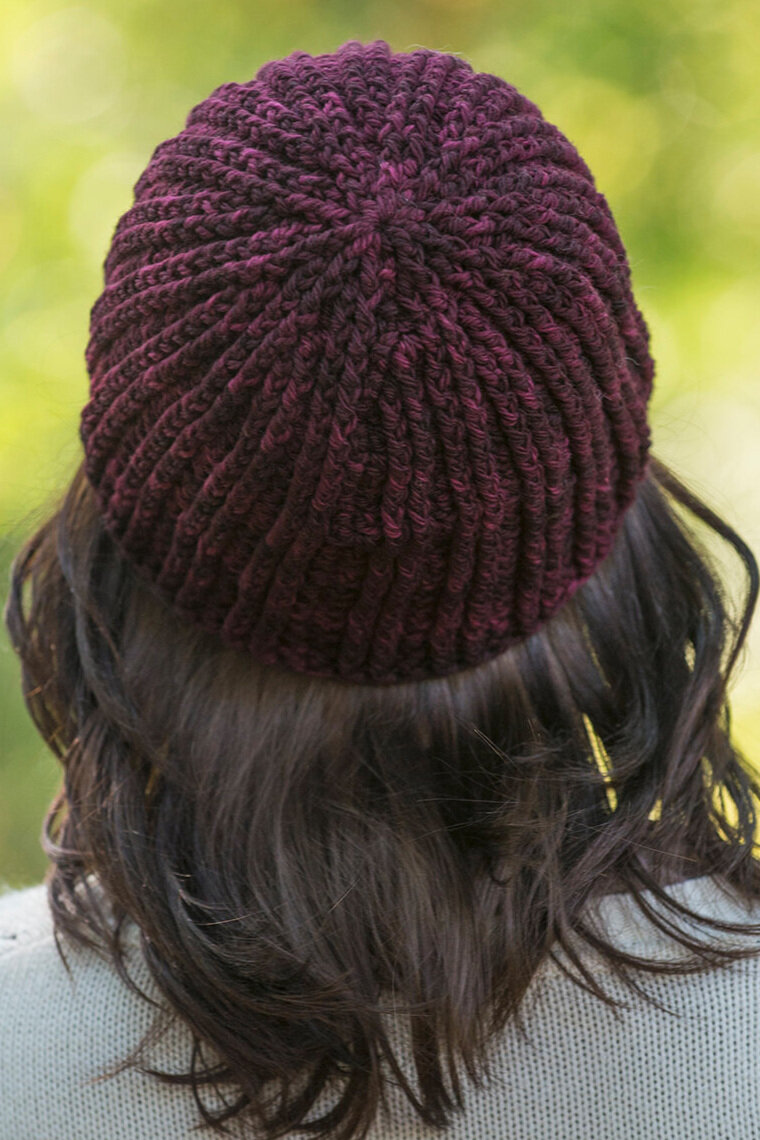  The back, close-up view of a deep wine-colored beanie on a person with brunette hair. 