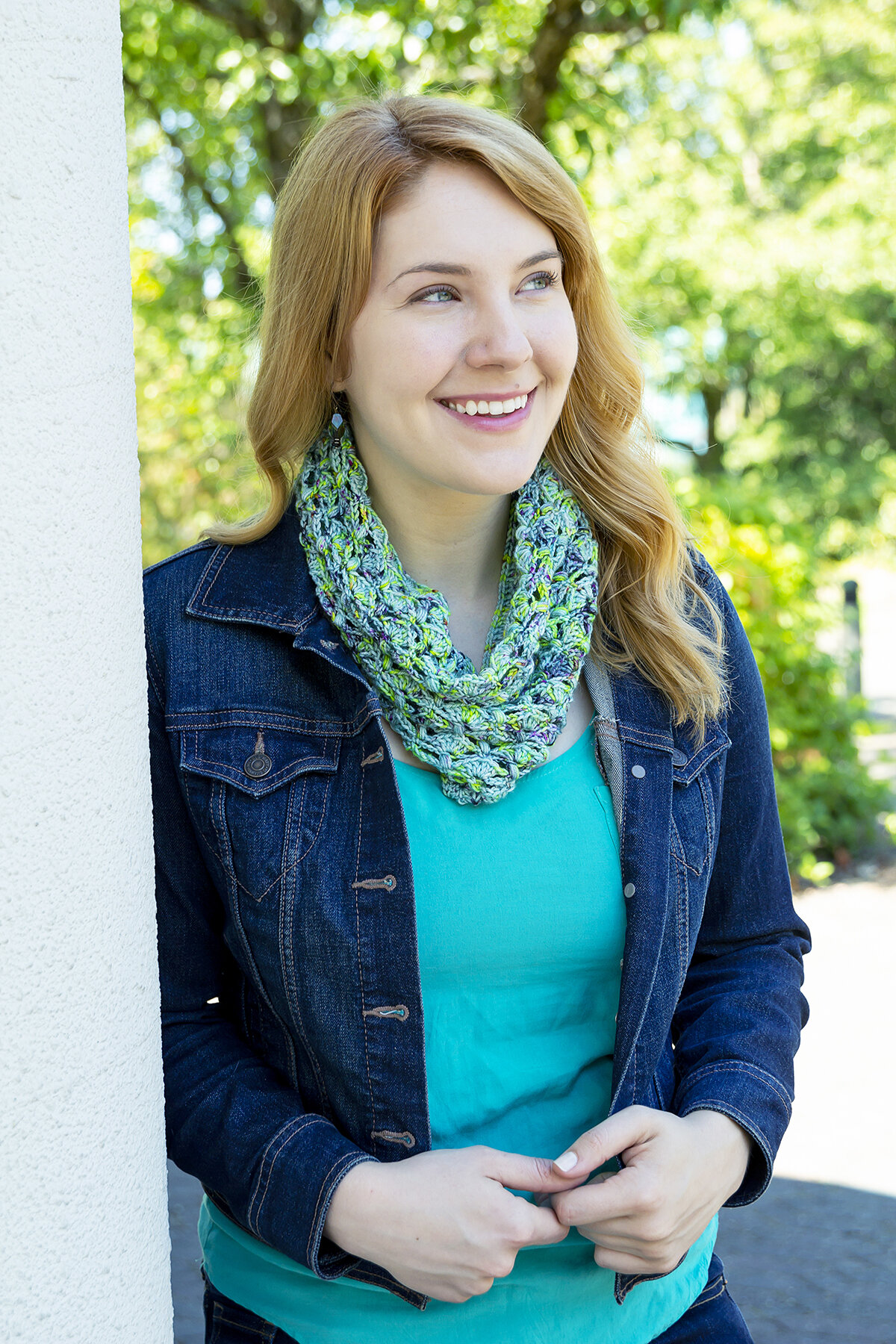  A woman in a denim jacket wearing a blue and green Anemone Cowl. 