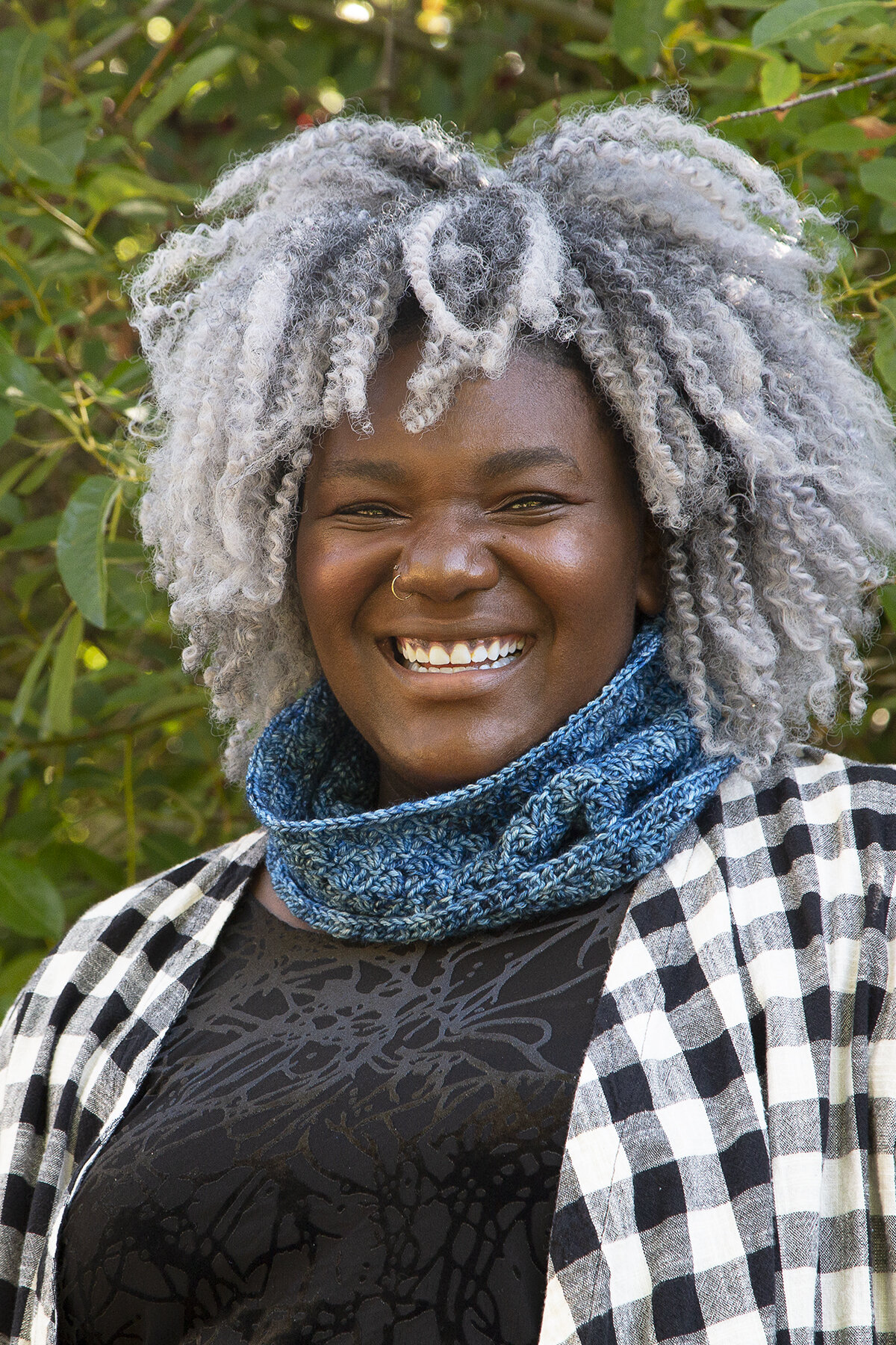 A smiling person wearing a blue Whirlpool Cowl around their neck.