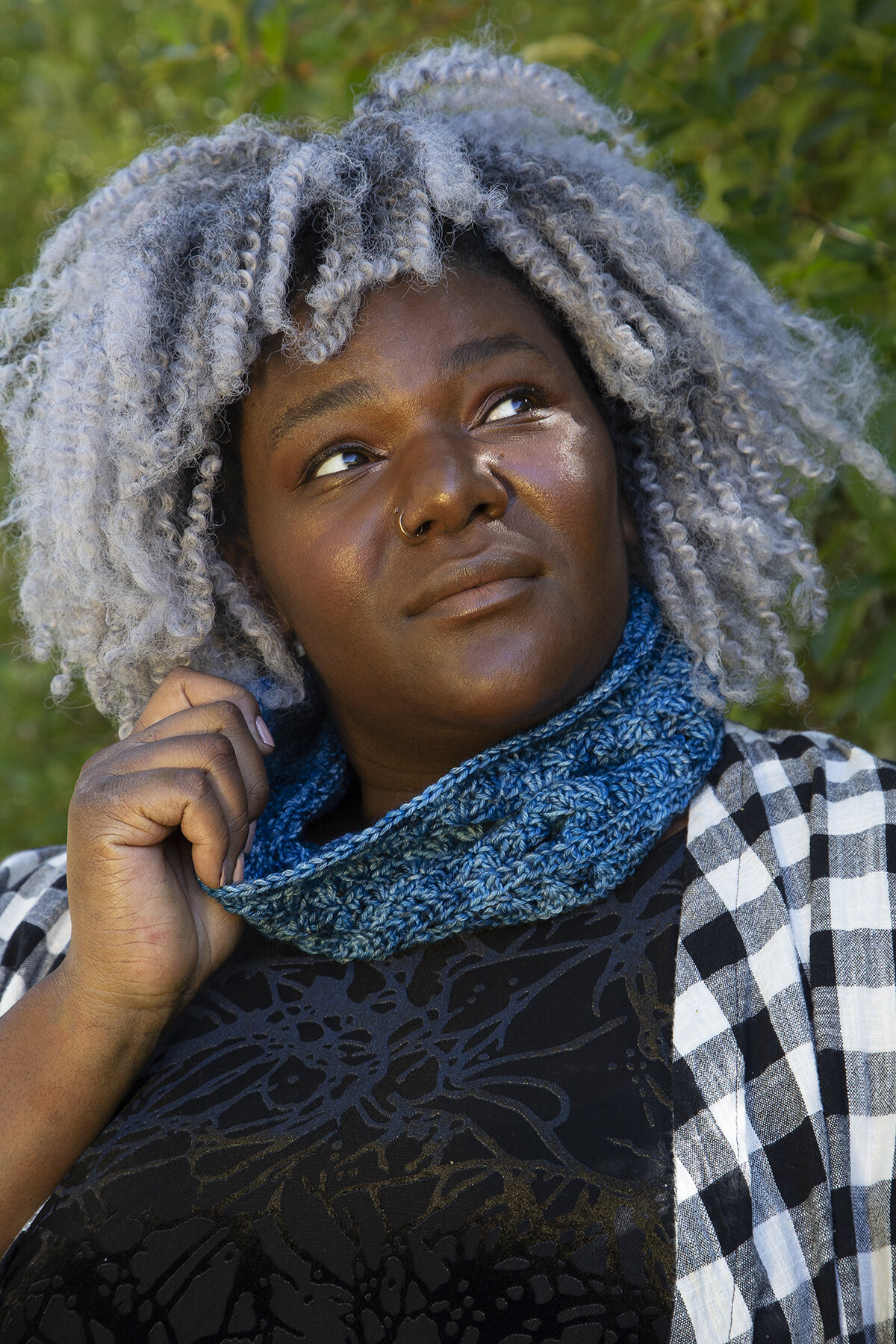 A person wearing a blue Whirlpool Cowl around their neck, holding on to one side of it.