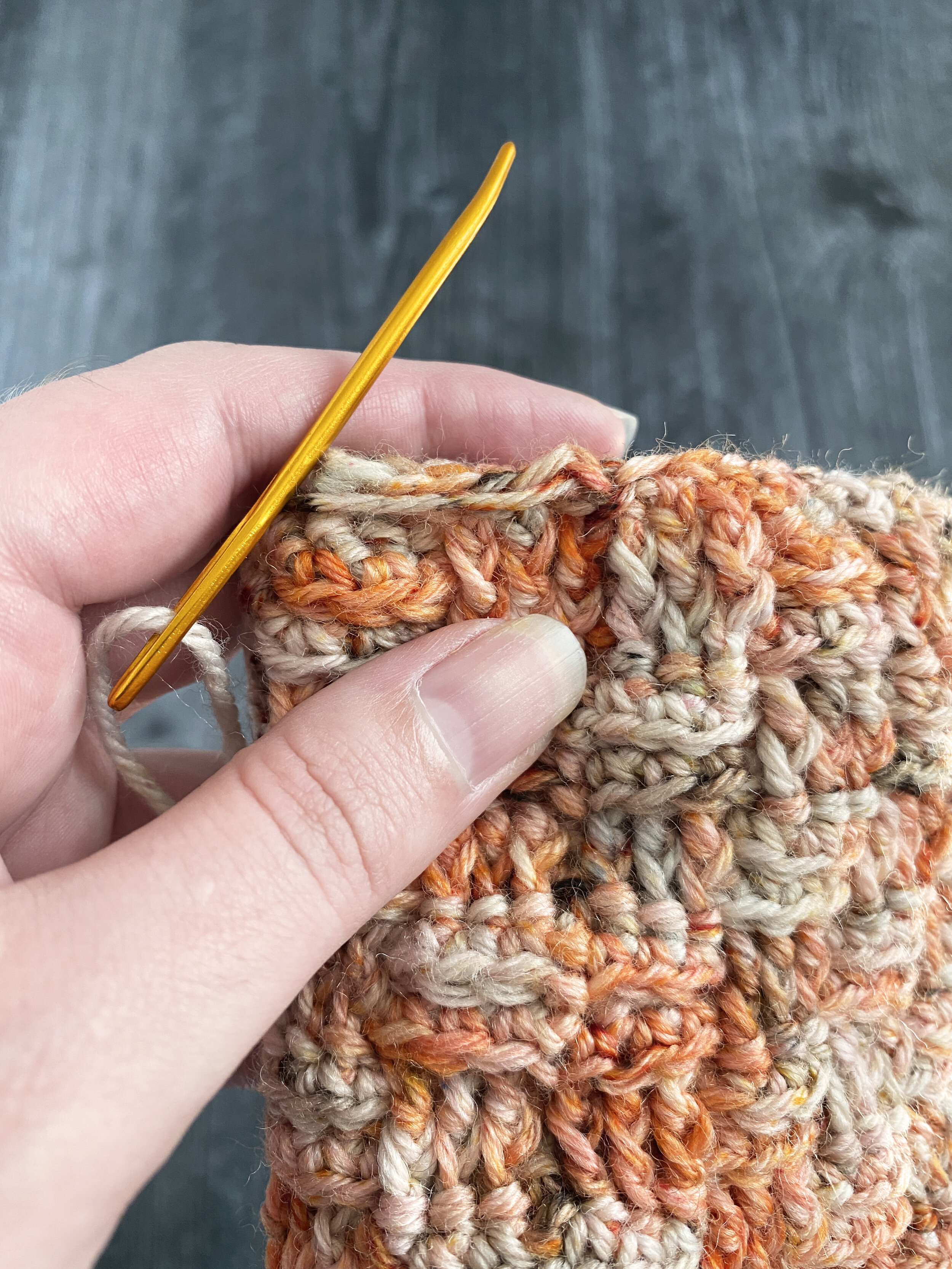 An up-close view of where to thread the yarn through the stitches to shape the pumpkin.