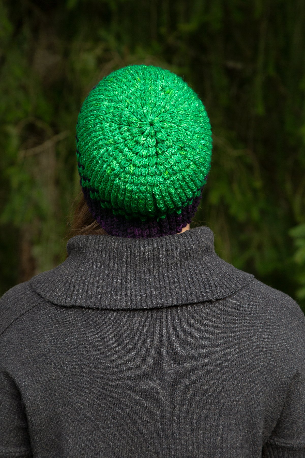 A person faces away, showing the back and crown of the Yarn Dragon Beanie on their head.