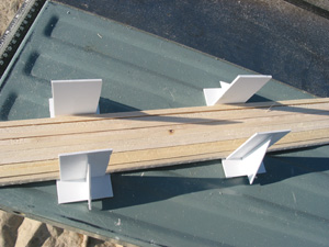  The next step is to bundle the ties for cross-cutting. A pair of home-made styrene cradles help establish a flat base for the tie bundle. Tie strips that are shorter due to knots are collected and made into shorter bundles. 