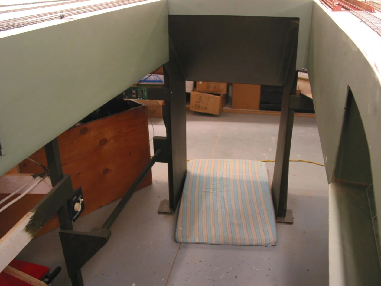 The crawl under entrance to this completely isolated industrial switching area was trimmed out with hardboard on all sides. A handrail here (left) and one in the outter aisle, assist operators regain verticality after going thru the chute.