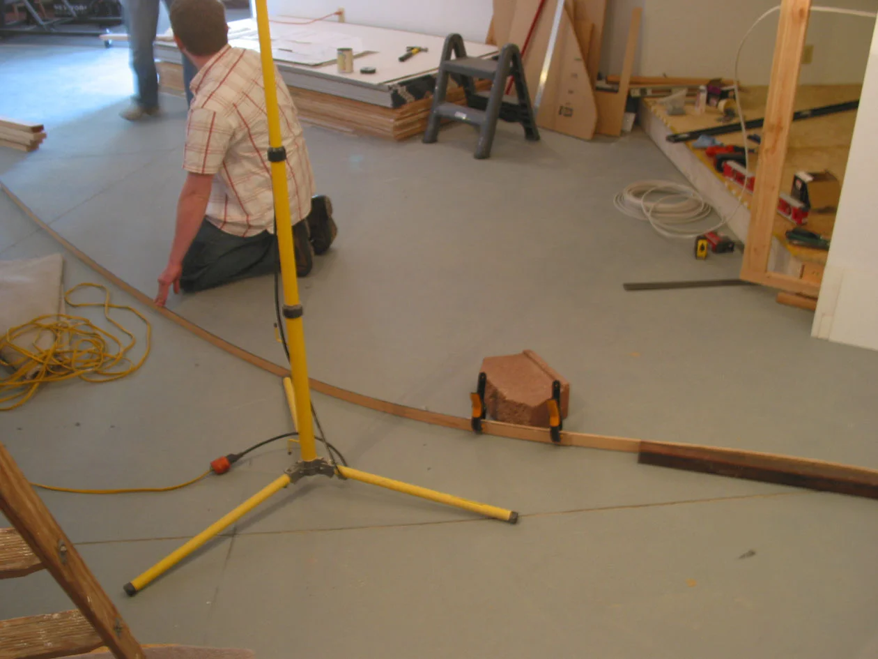 Since these new sud walls represent the winding valleys of West Virginia, they were definitely not straight. How to find their locations in the open space? Lots of plan checks and the use of splines. Here a landscape cinderblock serves to temporarily hold the spline in place until a line can be drawn.