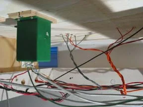 Wires are gathered, braided, and soldered as a group to their bus wire. To ease alignment and mounting of the Tortoise switch motors, vinyl underlayment wood is cut and drilled to allow mounting of the Tortoise. Slots on the edge of the board allow for adjustment of the motor before two screws affix it to the layout.