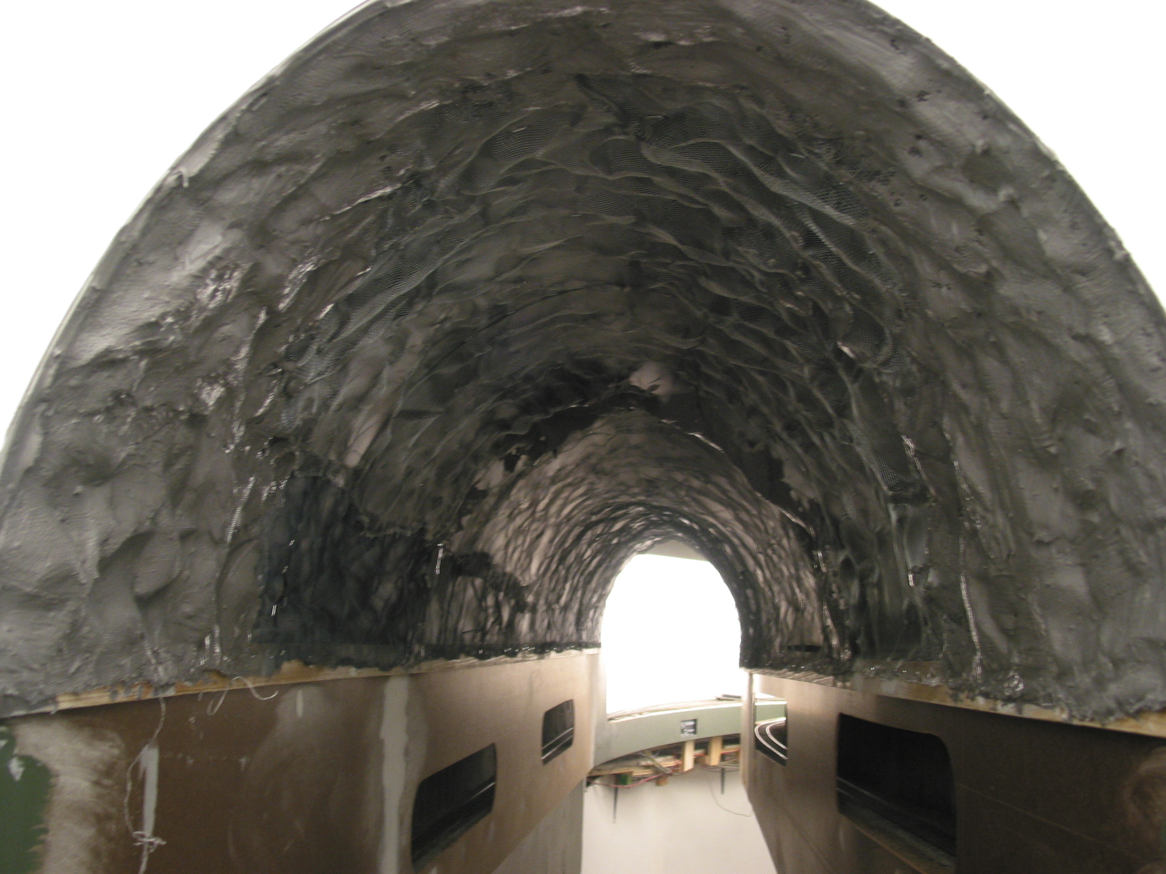  Looking at pictures of actual tunnels revealed a lot of gunnite/shotcrete sprayed over the rock and dirt to create a hard shell. And, it was lumpy vs. smooth. So I crumpled up aluminum screen wire, flattened, and stapled it to the wood as well. 