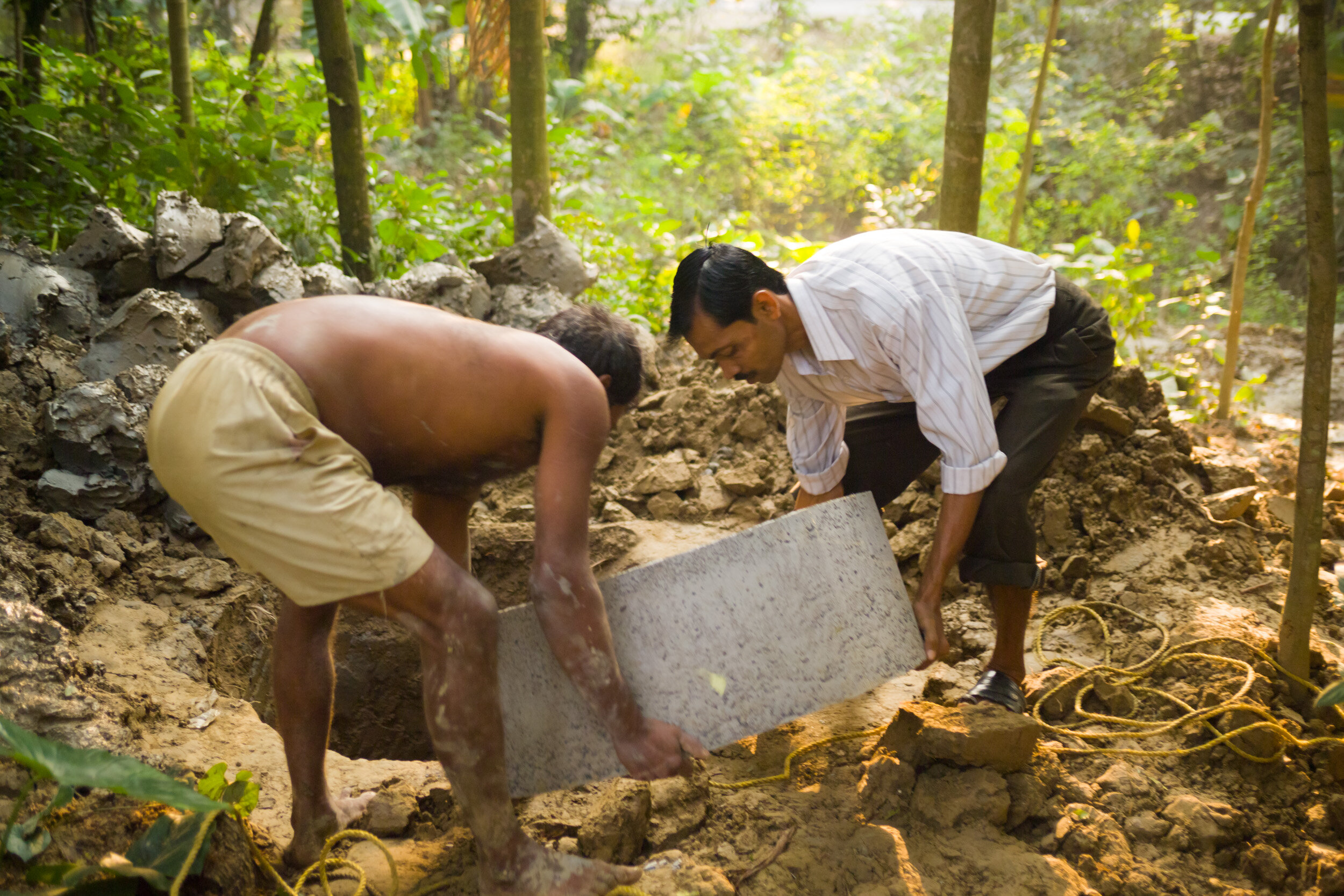 Once the hole is large enough, concrete cylinders are handed down to a worker in the hole. (Copy)