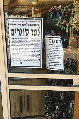 Posters in a shop window on Eilat Street in Tel Aviv’s garment district, March 7, 2018. (Simona Weinglass/Times of Israel)