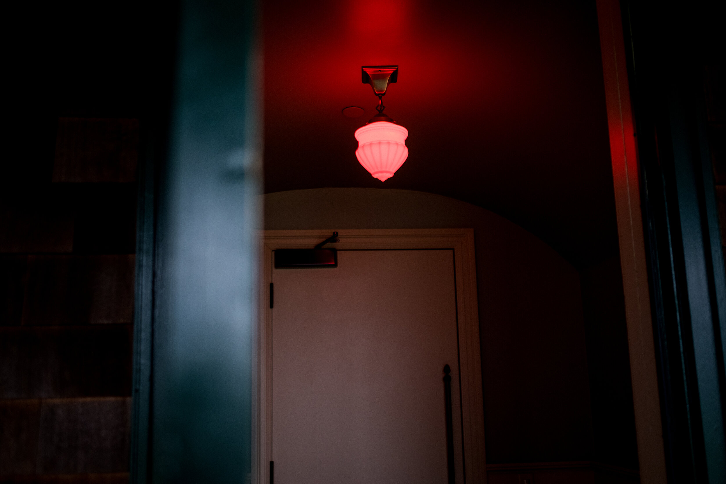  A red light demanding caution outside the doors of the theatre, indicating that the movie is currently screening. 