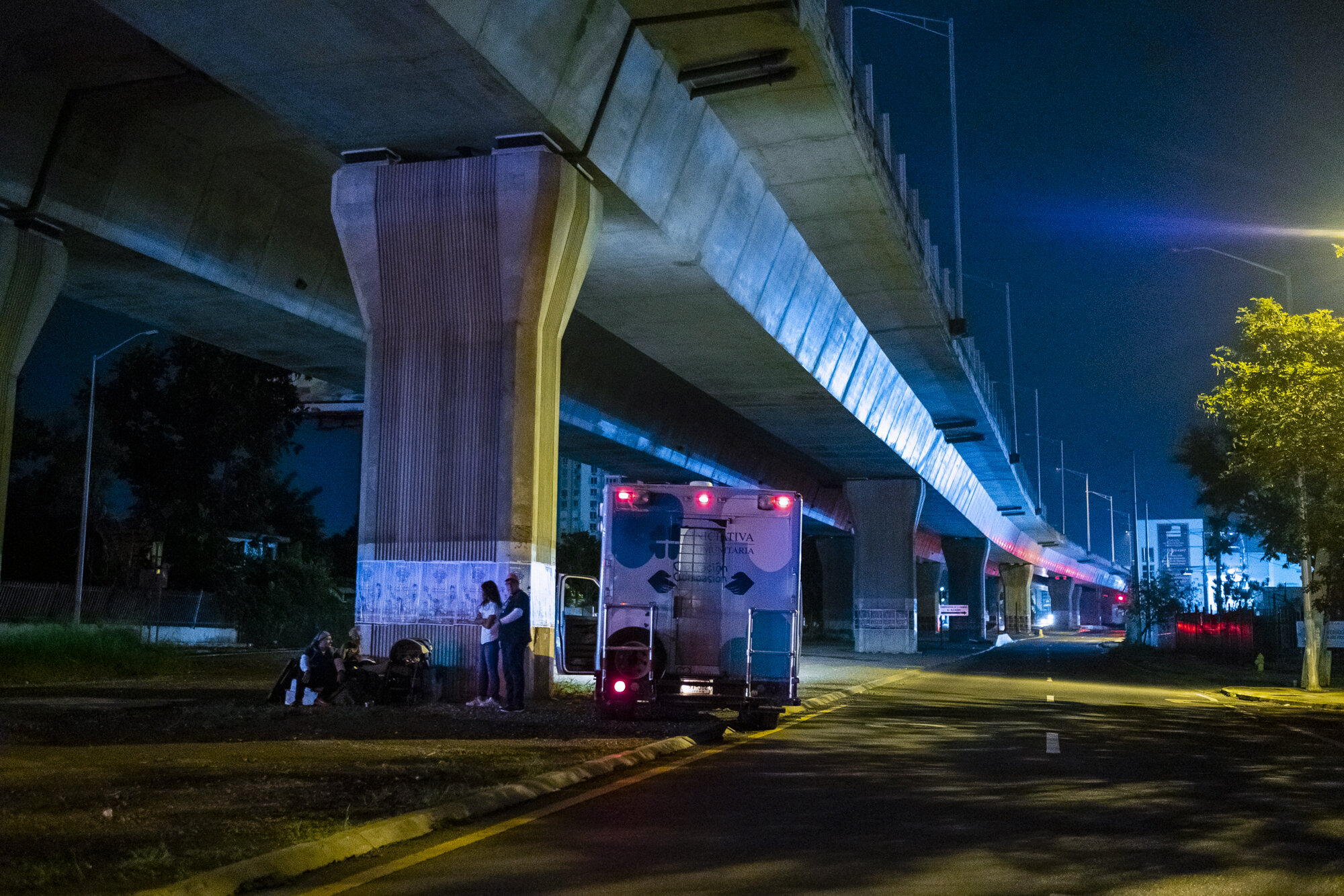  Iniciativa Comunitaria’s nocturnal outreach program tours San Juan every week. Tonight they stop under a highway bridge to offer food and comfort to an elderly homeless man.  