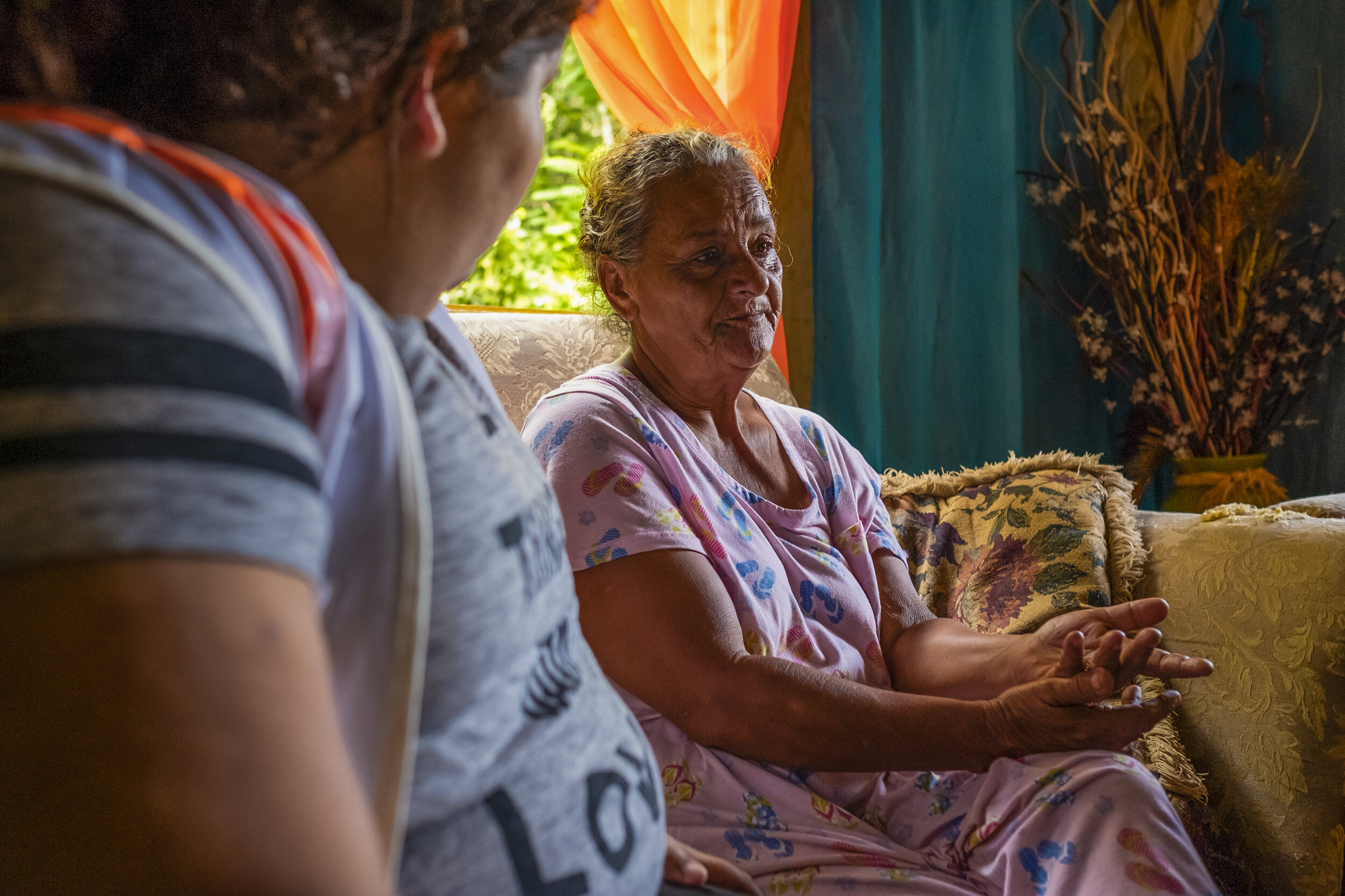  A nurse of Iniciativa de Paz listens to a new patient, Marguerita, explaining how she lost four children in a three-year span to Hurricane Maria, the contraction of meningitis in jail, and a hit and run under investigation.  