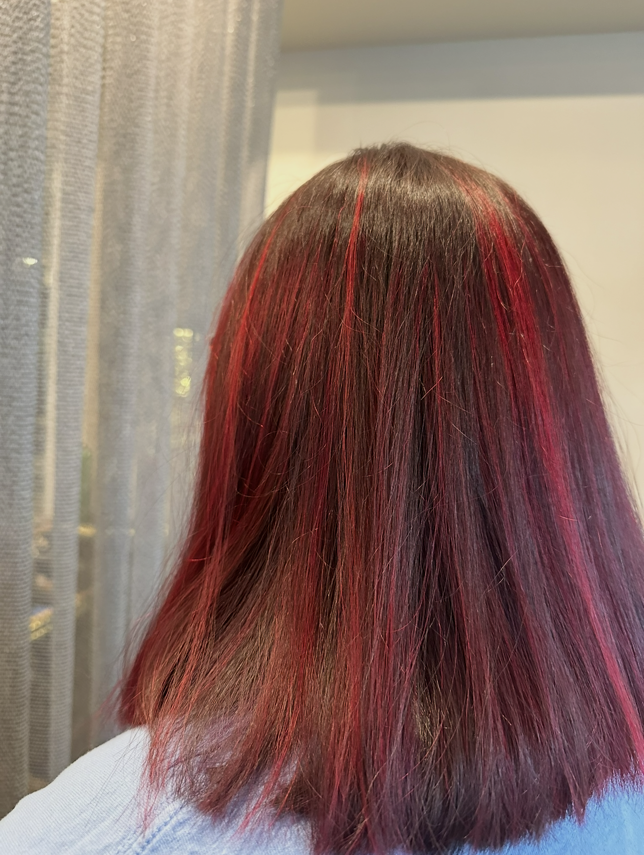 Cherry red peekaboo highlights on dark hair by Salon Sapphire stylist