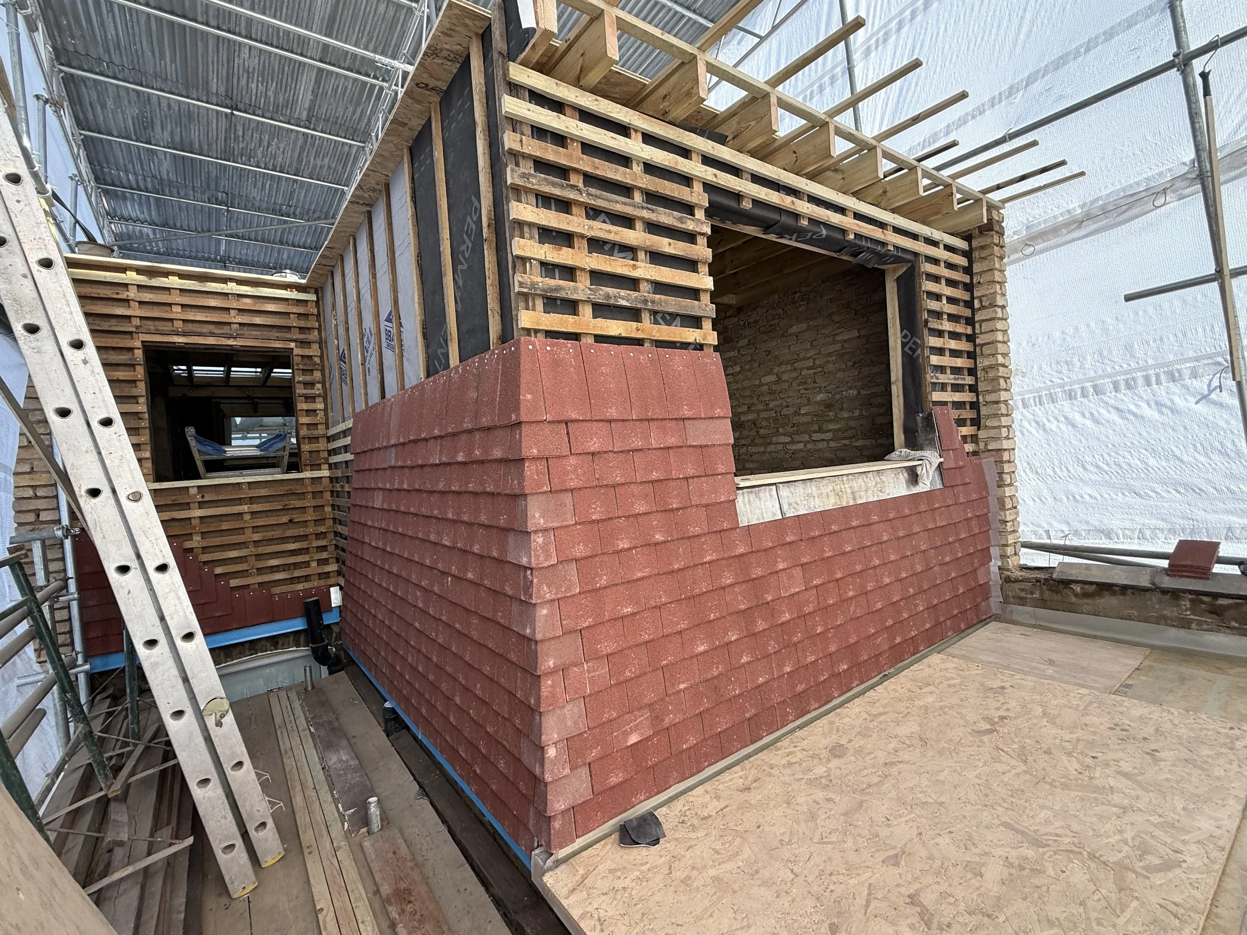 Loft conversion under construction with timber framing and brickwork