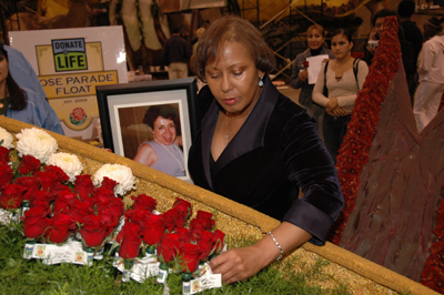 Carrying a framed photo of her donor, Eunice Sutton places her dedicated red rose in the float's heart-shaped garden. (Photo: Scott Weersing)