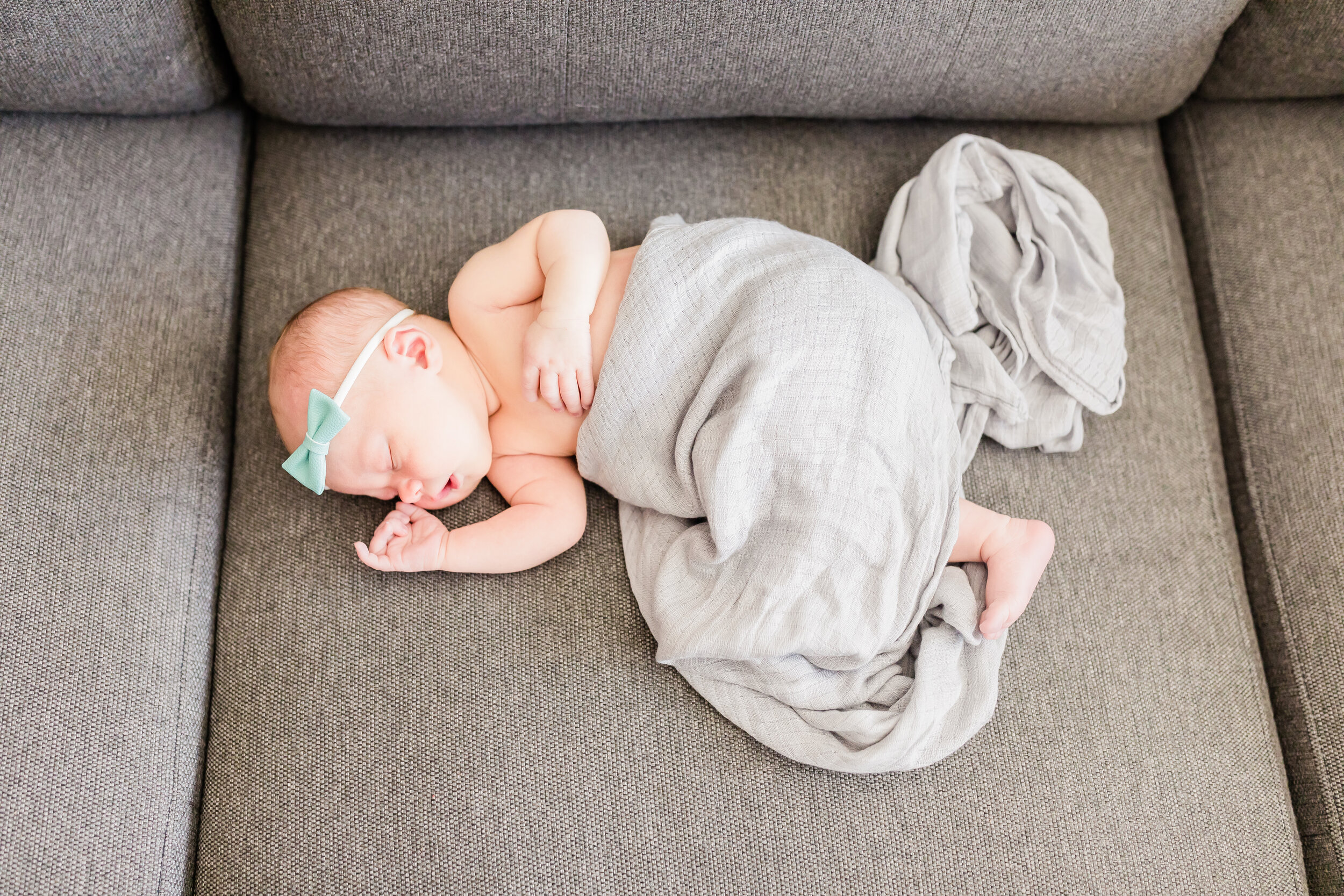 Newborn photographer, baby girl laying on couch in swaddle
