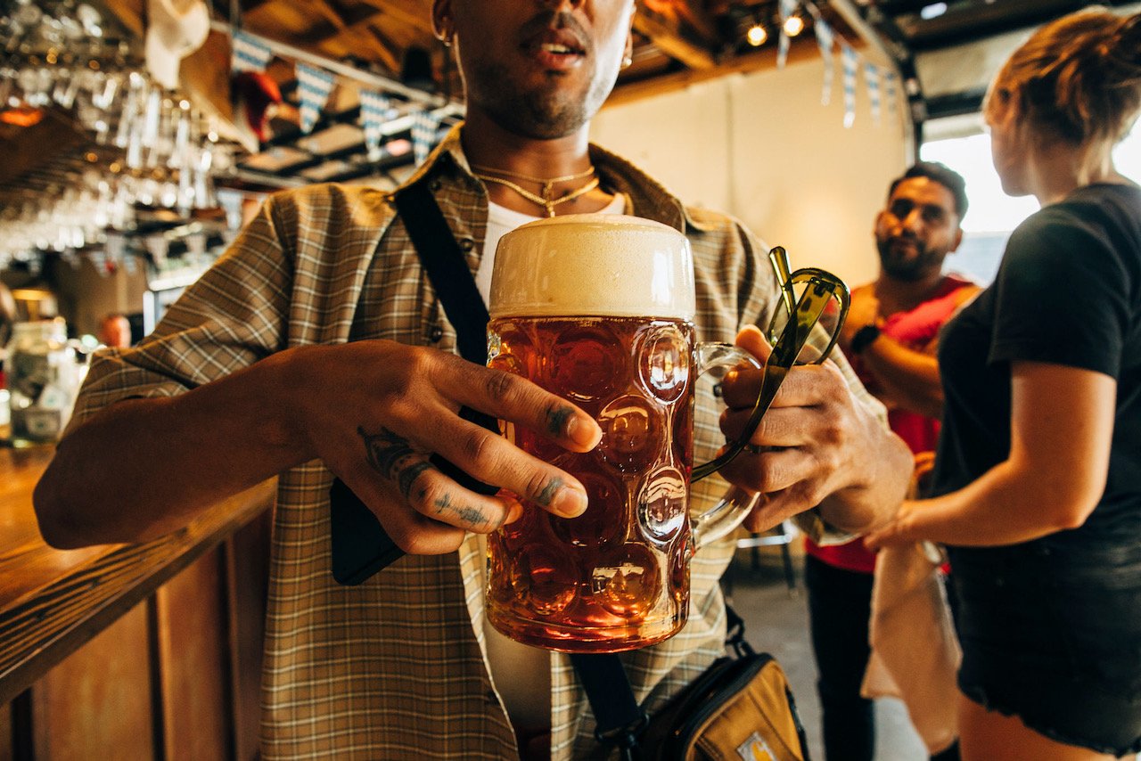 A person holding a stein of beer walking away from the bar