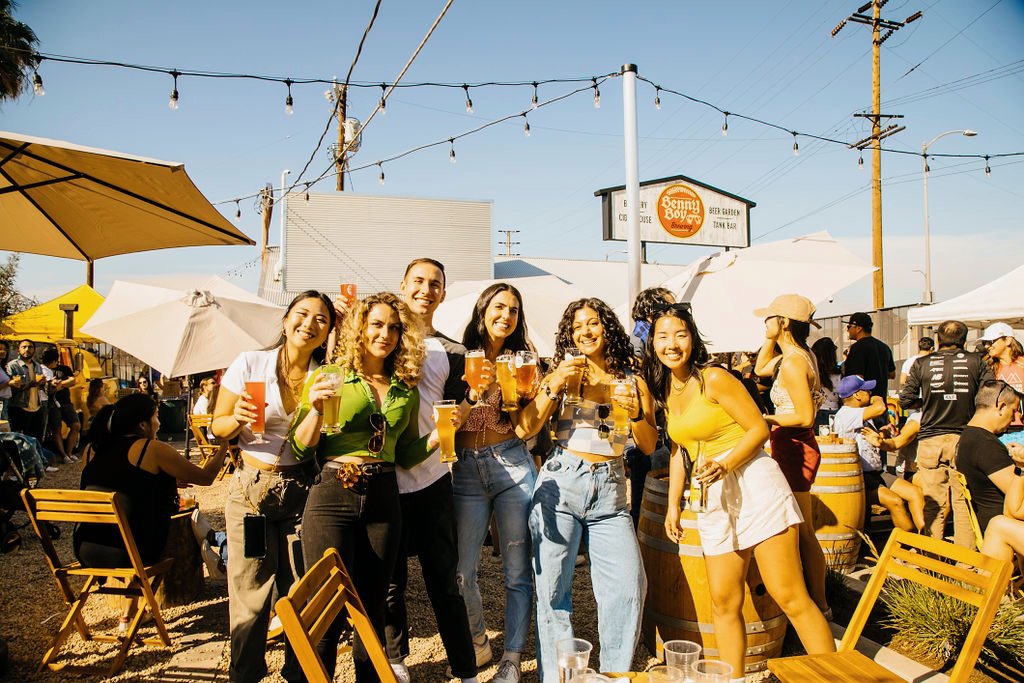 A group of people posing in the beer garden with the big sign in the background
