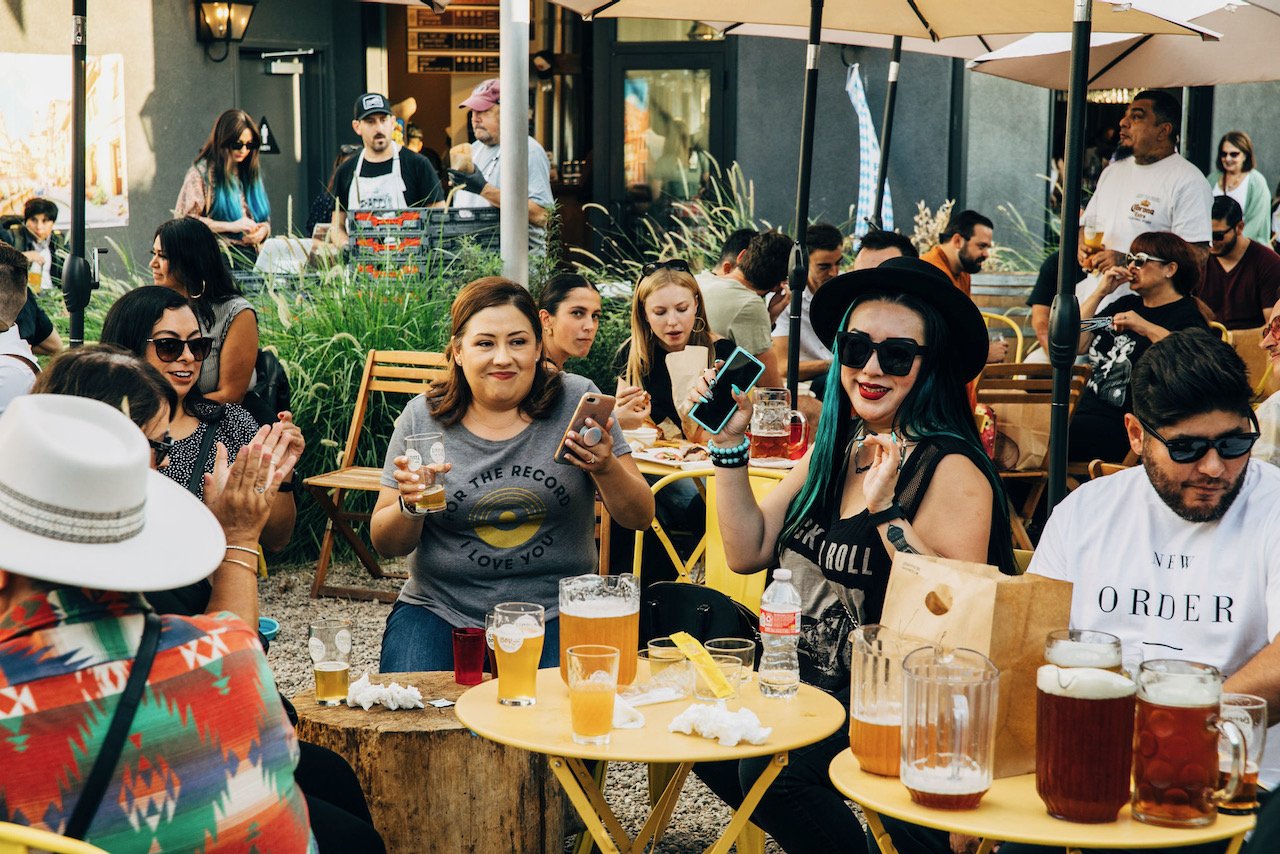 A group of people sitting around tables in the beer garden enjoying themselves